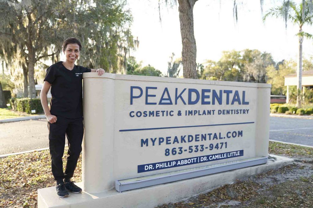 portrait of Dr. Little standing next to the outside sign of Peak Dental in Bartow Florida