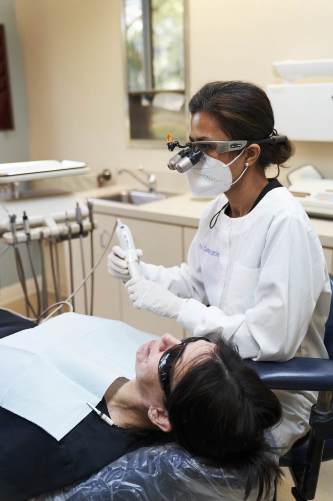 portrait of a dentist holding an intraoral camera while a dental patient sits in a dental exam chair
