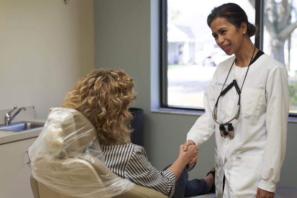 dr camille little, a dentist at peak dental in bartow florida, greeting a patient sitting in a dental exam chair